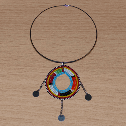 Collier africain de style tribal afro chic : il se compose d'un ras de cou en laiton rehaussé d'un long et large pendentif à motifs ethniques Massai fait de perles de rocaille multicolores et de chaînettes ornées de disques métalliques.