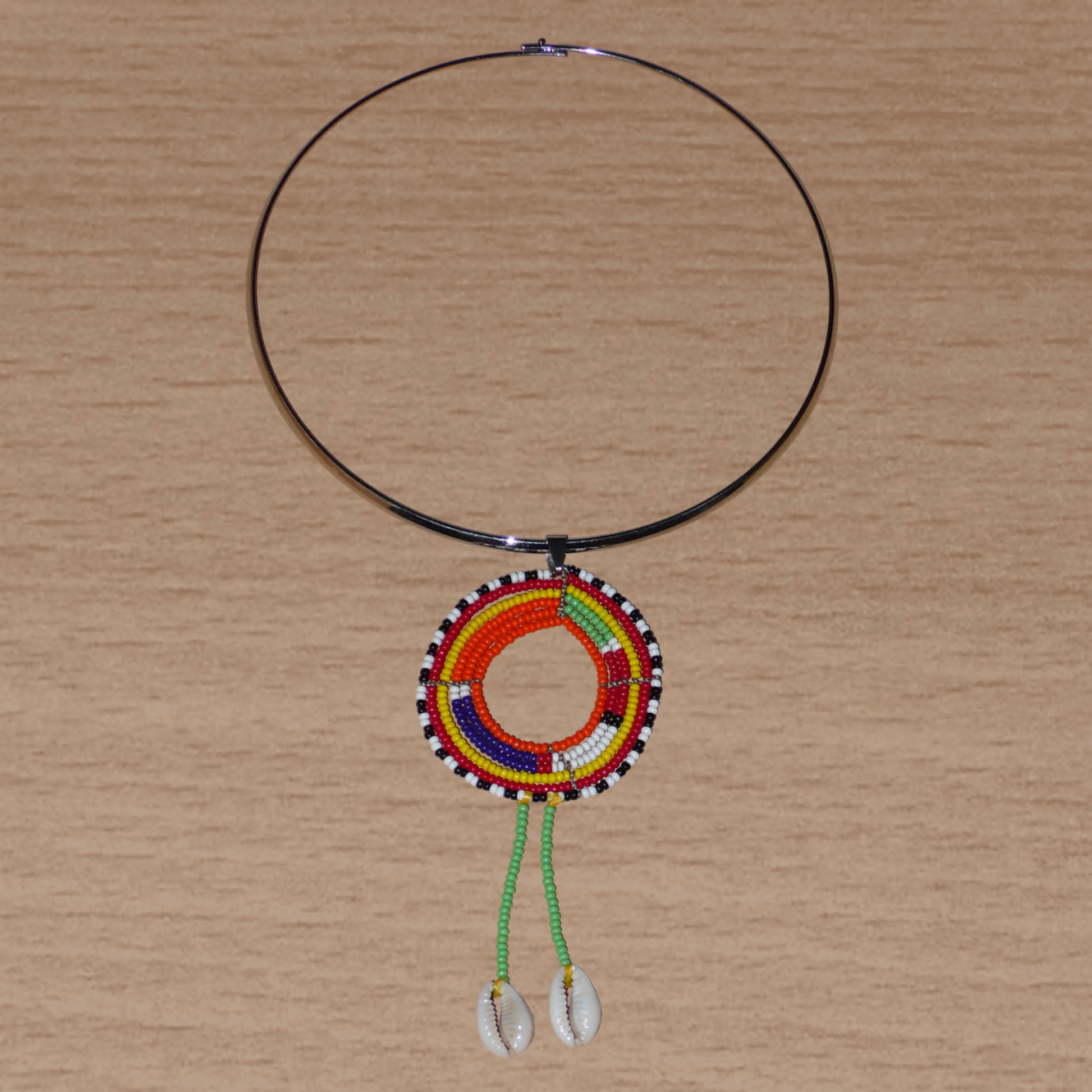 Collier africain se composant d'un ras de cou en laiton orné d'un long pendentif ethnique Massai en perles de rocaille vertes et multicolores et coquillages cauris.