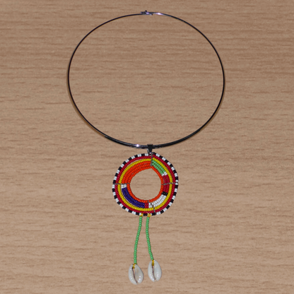 Collier africain se composant d'un ras de cou en laiton orné d'un long pendentif ethnique Massai en perles de rocaille vertes et multicolores et coquillages cauris.