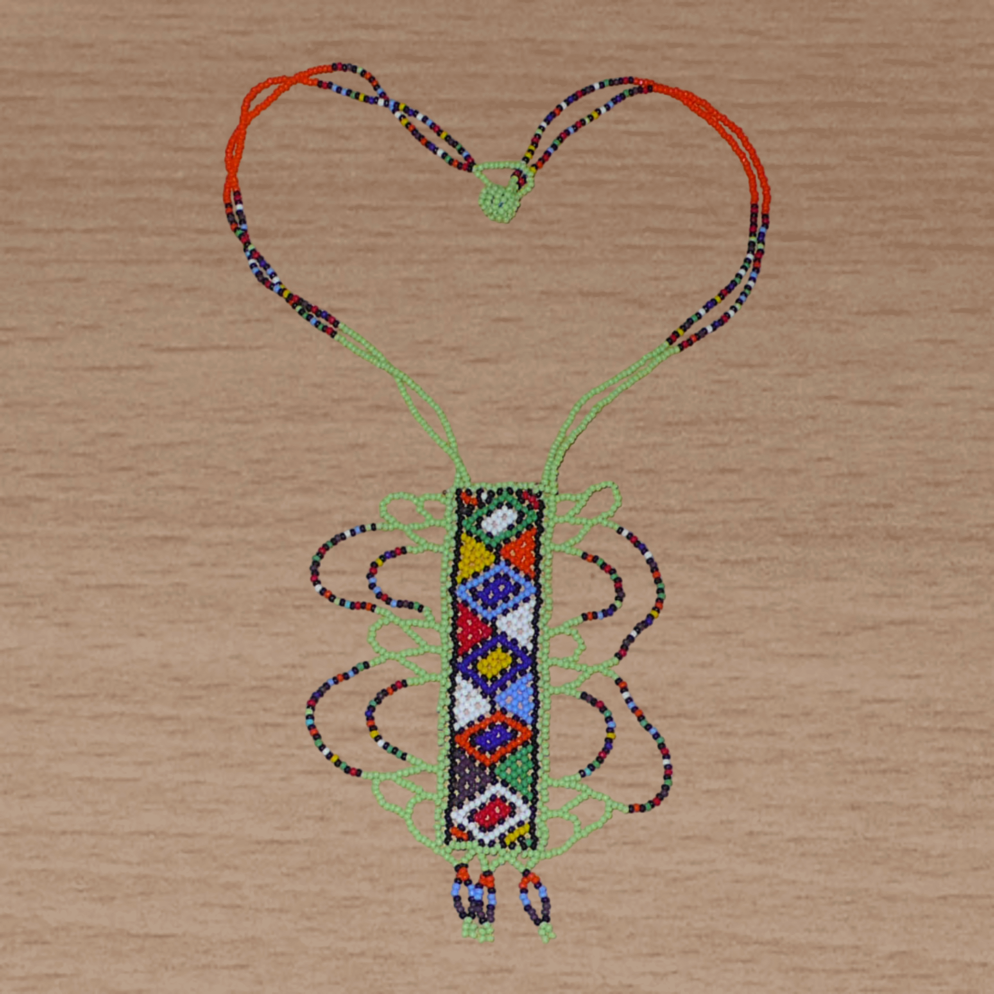 Collier sud-africain vert et multicolore à motifs ethniques zoulous, agrémenté d'un long et large pendentif en perles de rocaille.
