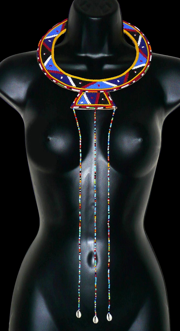 Collier africain traditionnel Massai composé de perles de rocaille principalement bleues brodées sur un morceau de cuir brut ; il se prolonge de longues franges perlées avec à leur base des coquillages cauris.