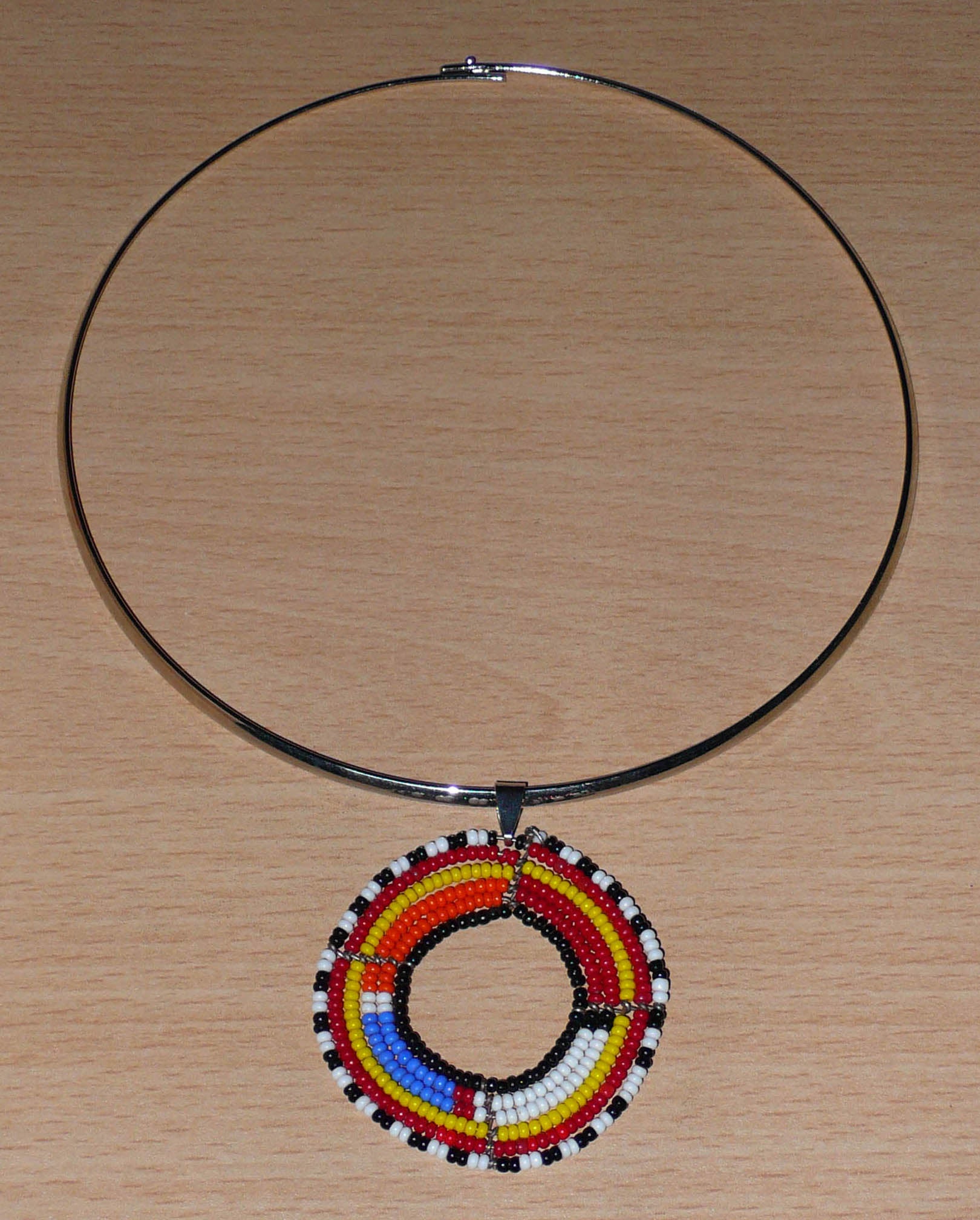 Collier ethnique fait d'un ras de cou en laiton orné d'un médaillon Massai composé de perles de rocaille multicolores.