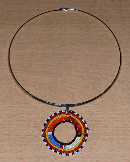 Collier ethnique fait d'un ras de cou en laiton orné d'un médaillon Massai composé de perles de rocaille multicolores.