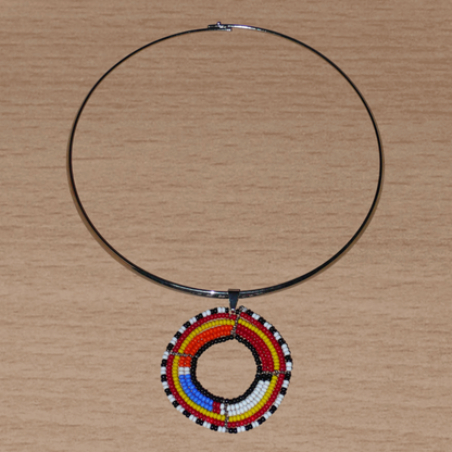 Collier ethnique fait d'un ras de cou en laiton orné d'un médaillon Massai composé de perles de rocaille multicolores.