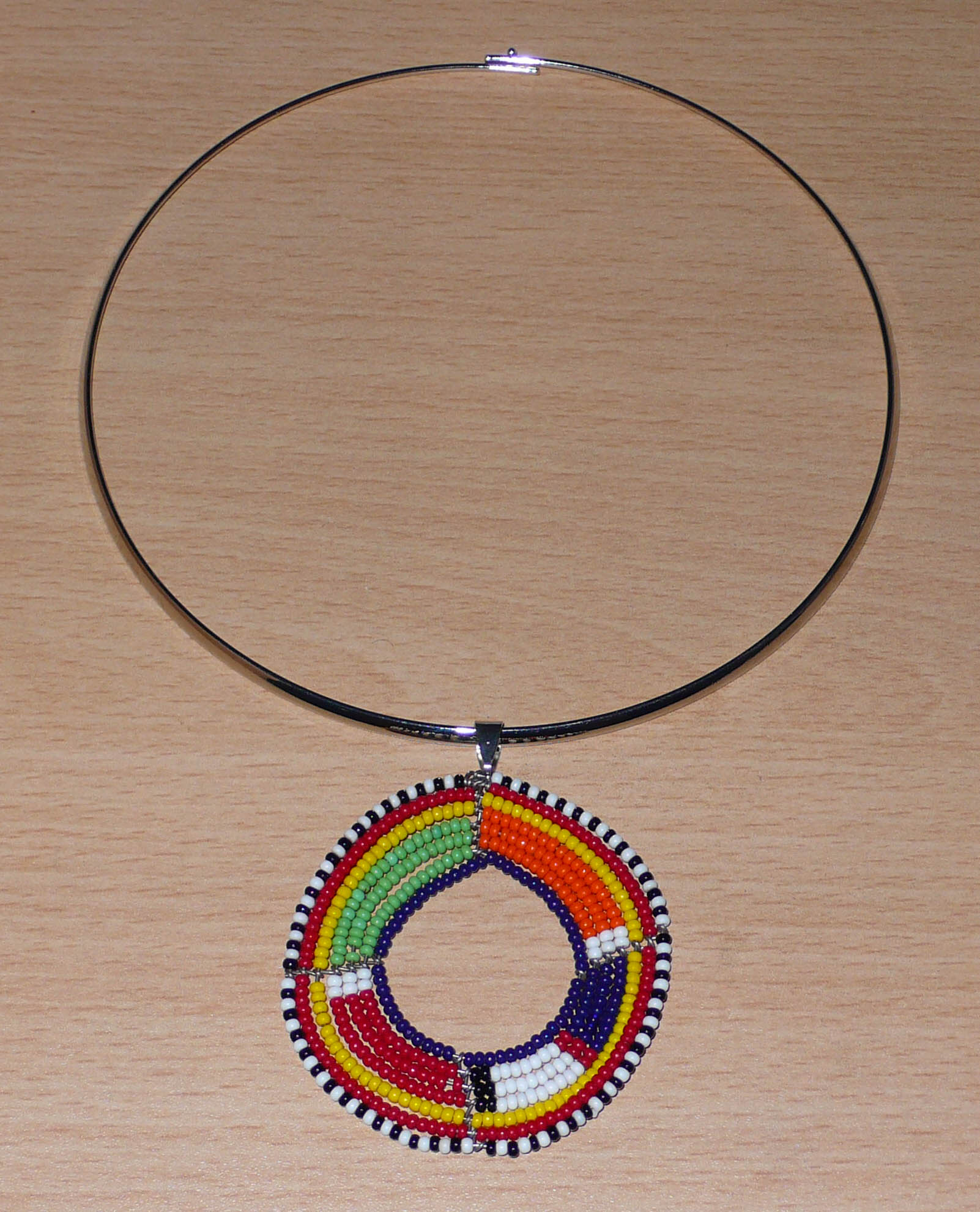 Bijou africain composé d'un collier ras de cou en laiton rehaussé d'un pendentif Massai rond fait de perles de rocaille multicolores.