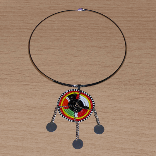 Bijou africain composé d'un ras de cou en laiton agrémenté d'un pendentif fait de perles de rocaille noires et multicolores et décoré de petits disques métalliques.