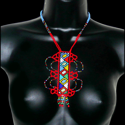 Collier sud-africain zoulou rouge et multicolore agrémenté d'un long et large pendentif fantaisie à motifs ethniques traditionnels. Il se compose de perles de rocaille et s'attache avec un fermoir à boule.