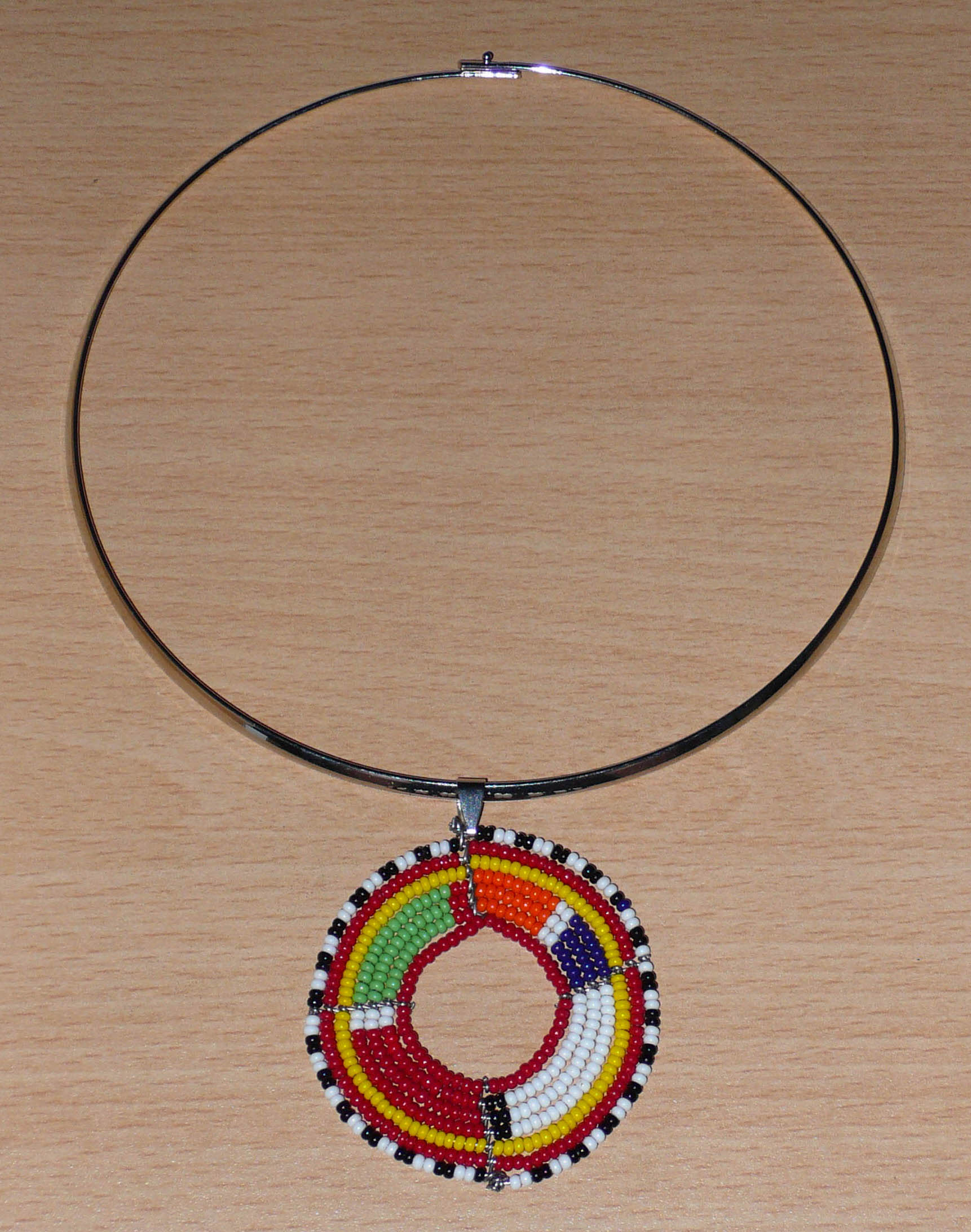 Collier africain composé d'un ras de cou en laiton rehaussé d'un médaillon Massai fait de perles de rocaille rouges et multicolores.