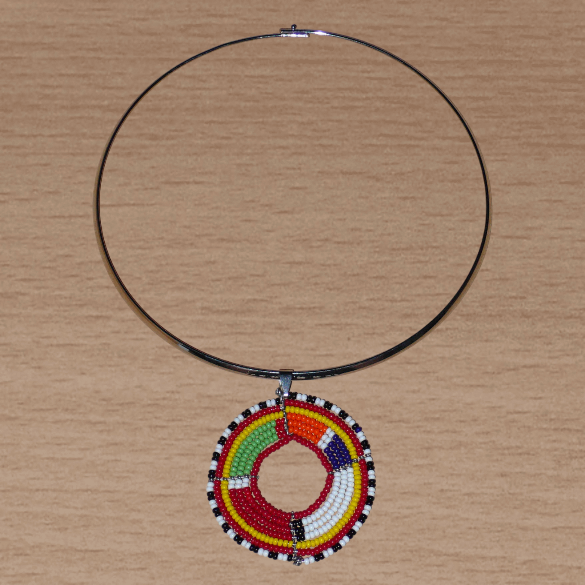Collier africain composé d'un ras de cou en laiton rehaussé d'un médaillon Massai fait de perles de rocaille rouges et multicolores.