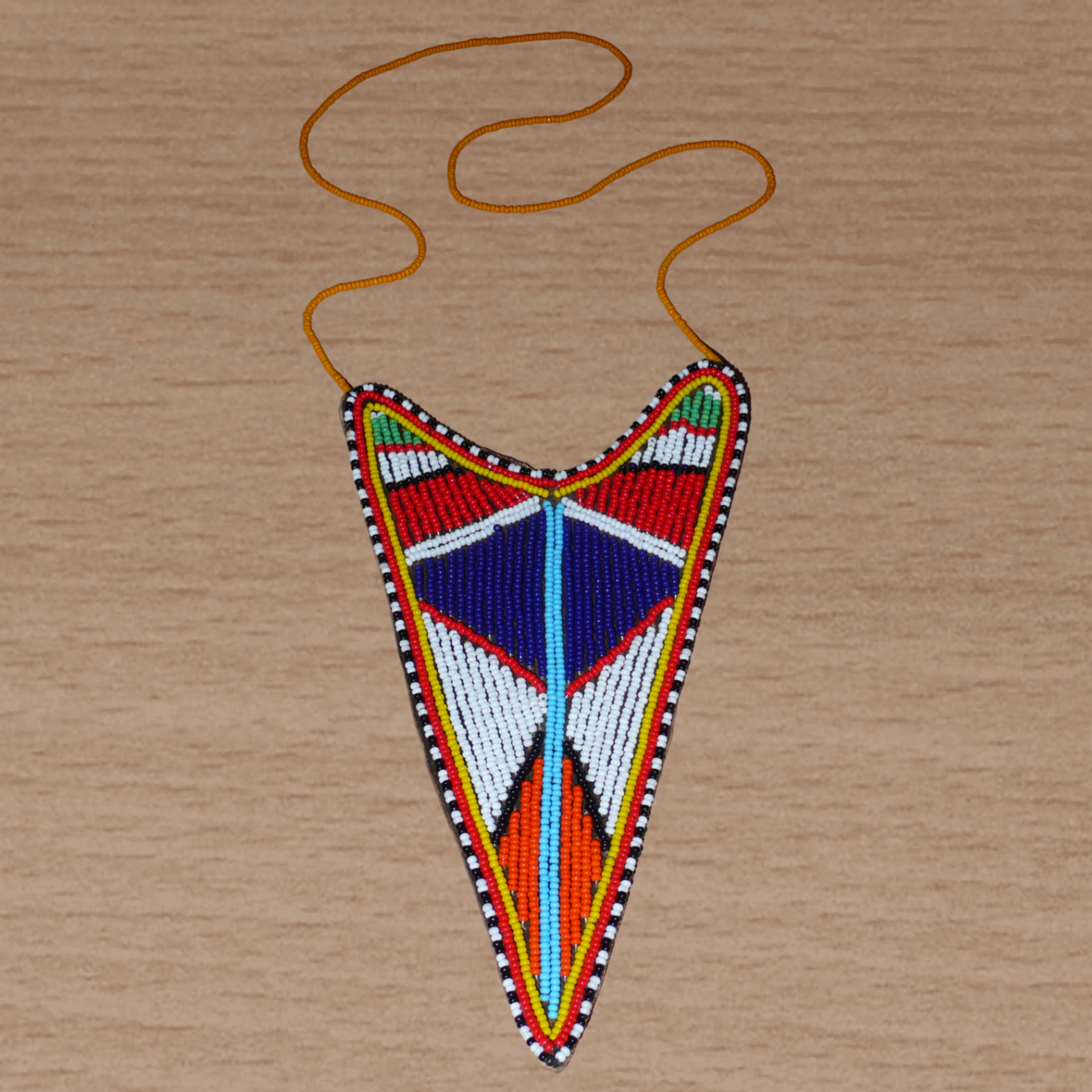 Long collier africain tribal de tradition Massai agrémenté d'un long et large pendentif aux couleurs et motifs ethniques composé d'une broderie de perles de rocaille multicolores.