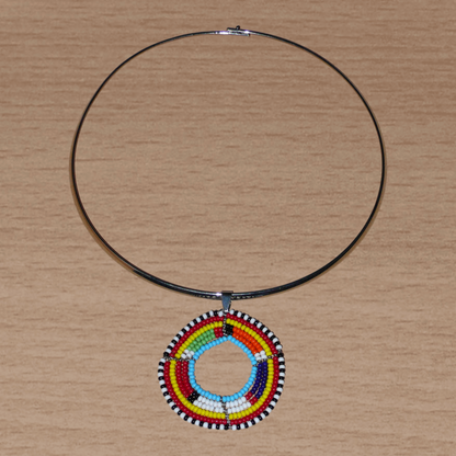 Collier africain ethnique composé d'un ras de cou en laiton agrémenté d'un médaillon traditionnel Massai fait de perles de rocaille multicolores.
