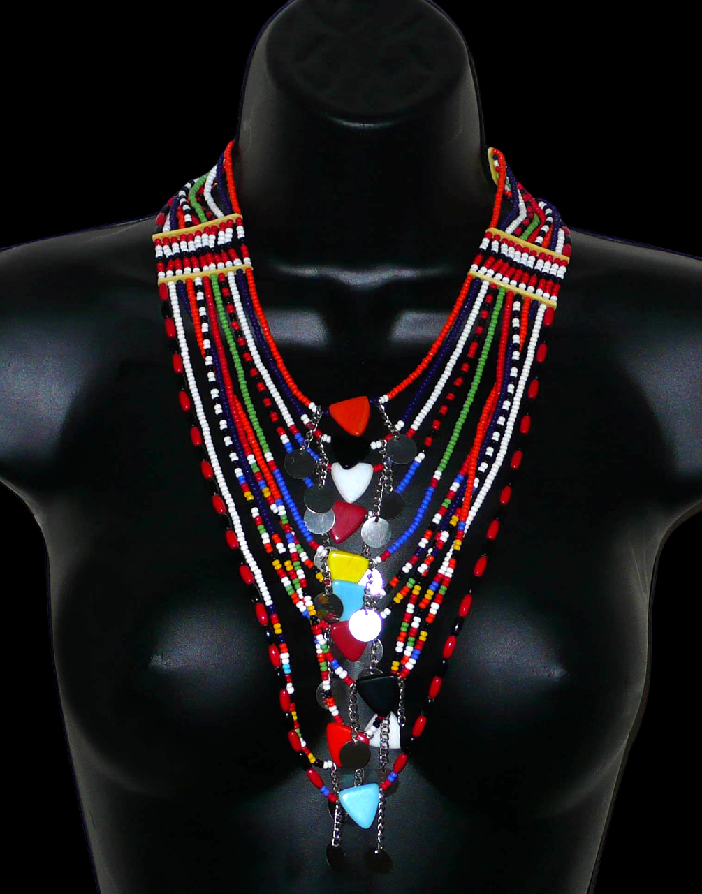 Collier africain traditionnel Massai composé de onze rangées de perles de rocaille et de plastique multicolores. Des perles triangulaires colorées et des pastilles en métal décorent le collier en son centre. Il mesure 38 cm de long, avec une longueur de tour de cou de 46 cm. Photographié sur un mannequin. Timeless Fineries