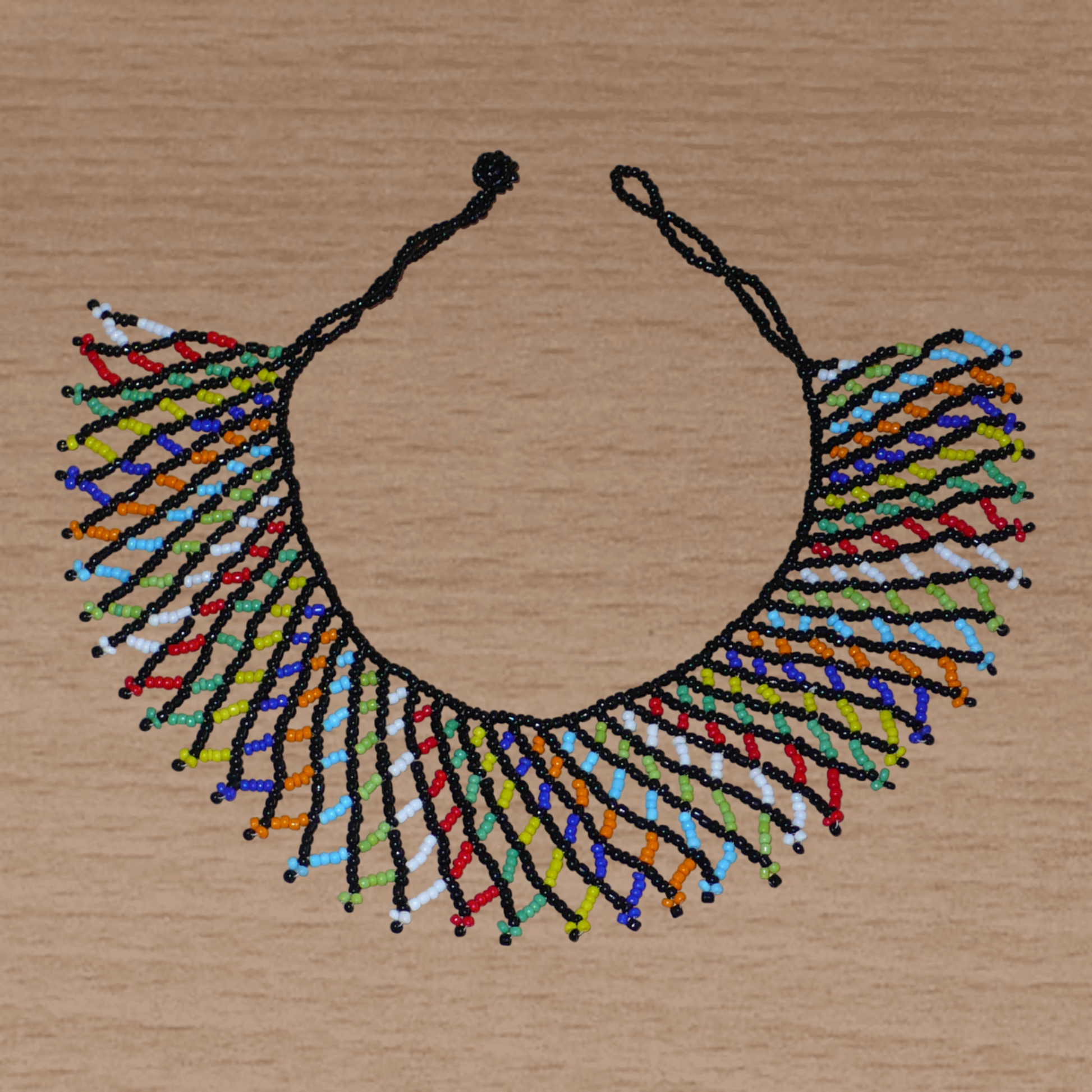 Collier africain zoulou traditionnel composé d'une dentelle de perles de rocaille noires et multicolores entrelacées.
