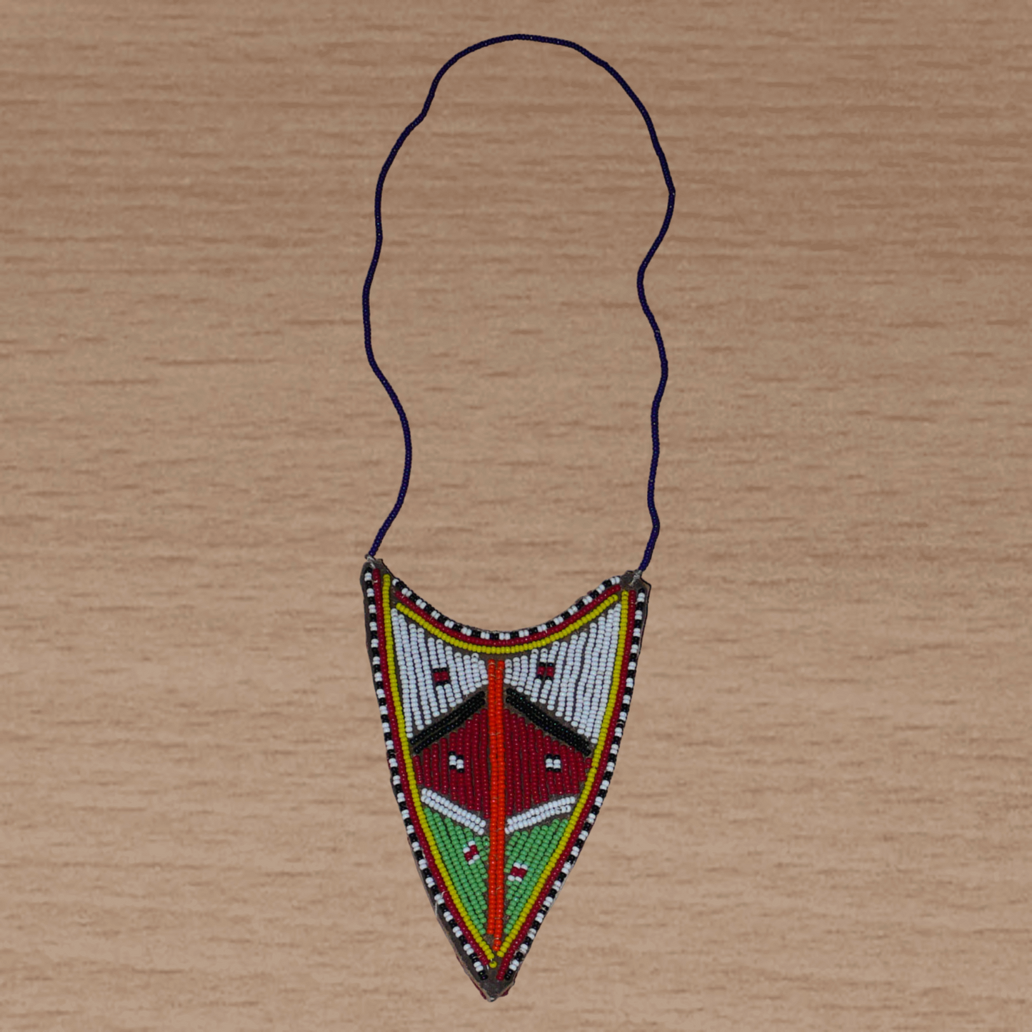 Collier africain tribal de tradition Massai orné d'un long et large pendentif composé d'une broderie de perles de rocaille principalement rouges, vertes et blanches brodées sur un morceau de cuir brut.