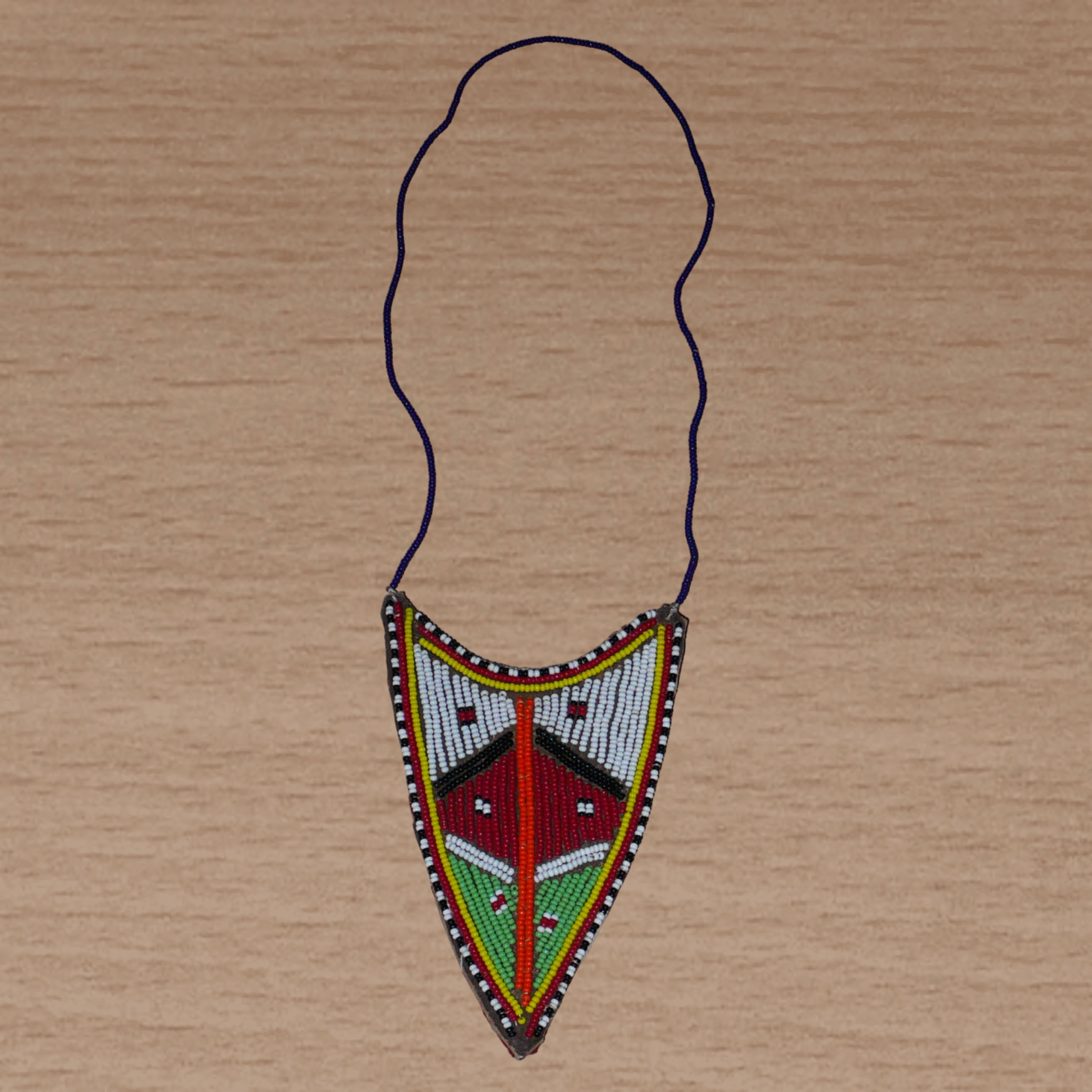 Collier africain tribal de tradition Massai orné d'un long et large pendentif composé d'une broderie de perles de rocaille principalement rouges, vertes et blanches brodées sur un morceau de cuir brut.