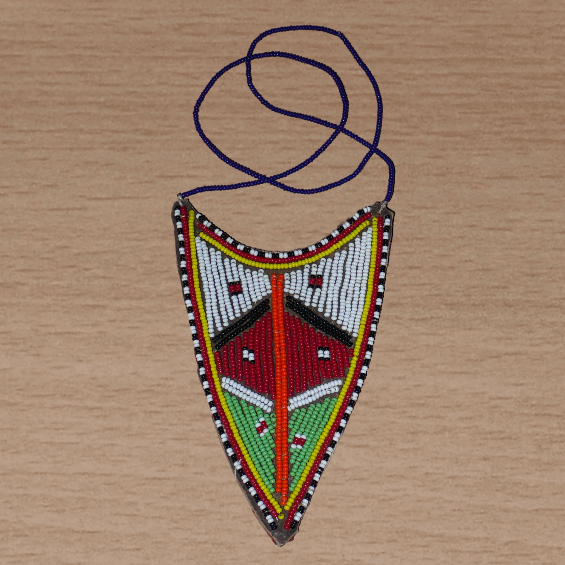 Collier africain tribal de tradition Massai orné d'un long et large pendentif composé d'une broderie de perles de rocaille principalement rouges, vertes et blanches brodées sur un morceau de cuir brut.