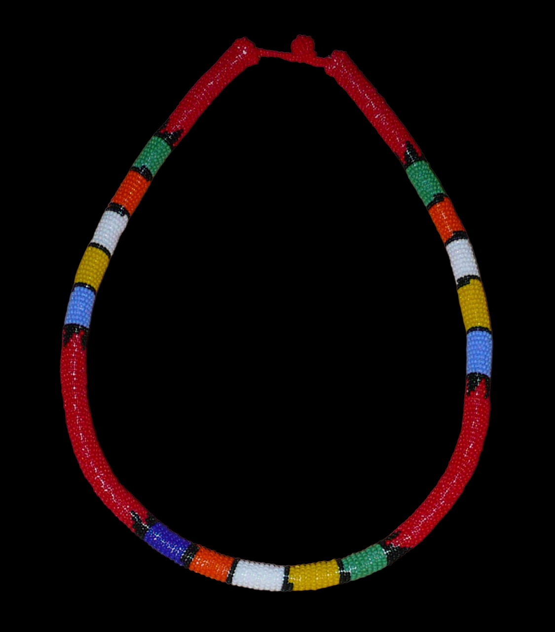 Collier sud-africain tubulaire rouge et multicolore. Composé d'un tube de plastique autour duquel sont enroulées des minuscules perles de rocaille rouges alternées avec des motifs ethniques traditionnels zoulous en bleu, jaune, blanc, orange et vert. Le collier mesure 24 cm de long (de la nuque jusqu'à la base du collier), la longueur du tour de cou du collier est 60 cm, et son épaisseur est de 1 cm. Il s'attache avec un fermoir à boule. Présenté sur un fond noir. Timeless Fineries