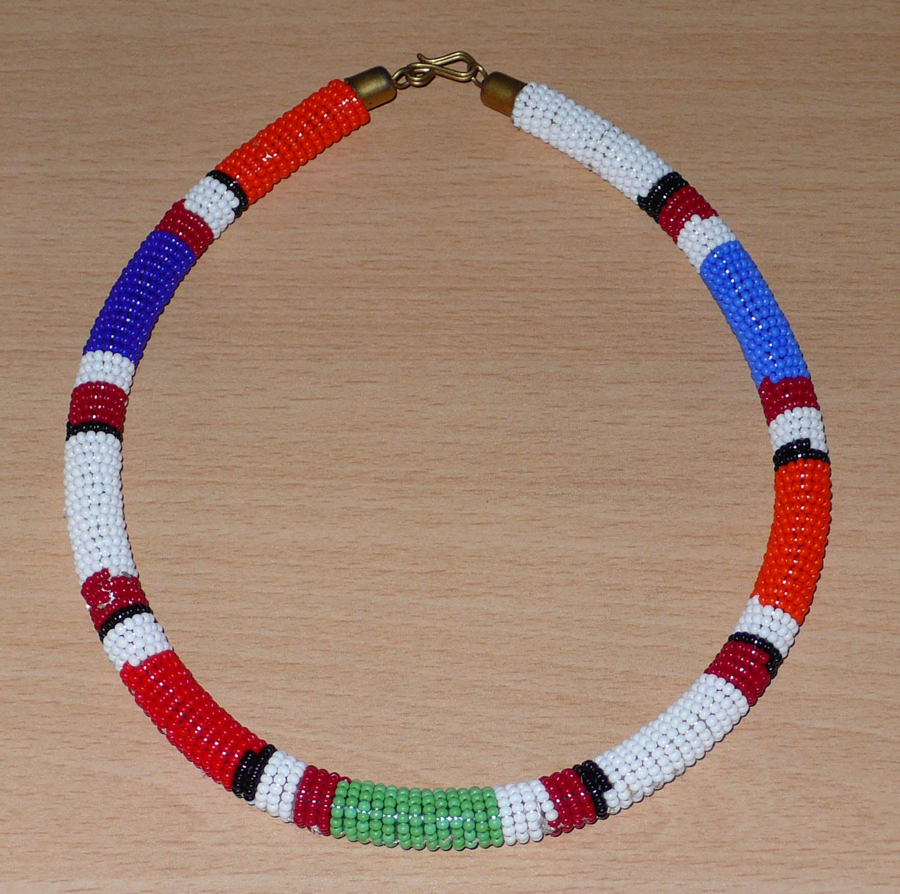 Collier africain tubulaire à motifs ethniques Massai composé de perles de rocaille multicolores tissées et enroulées autour d'un tube en plastique.