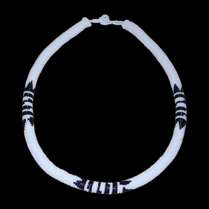 Collier africain zoulou blanc à motifs ethniques traditionnels noirs composé perles de rocaille tissées et enroulées autour d'un tube en plastique.