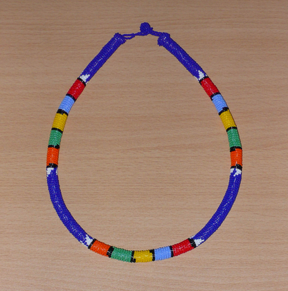 Collier sud-africain tubulaire bleu à motifs zoulous multicolores composé de perles de rocaille enroulées autour d'un tube.