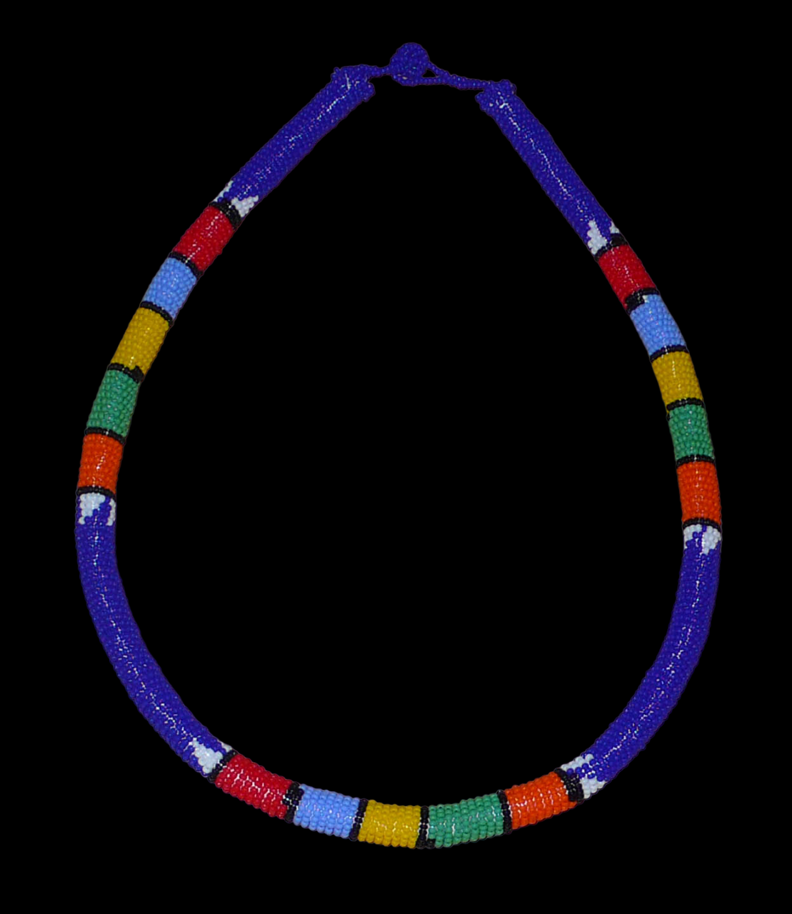 Collier sud-africain tubulaire bleu et multicolore. Il se compose d'un tube de plastique autour duquel sont enroulées des petites perles de rocaille bleues alternées avec des motifs ethniques traditionnels zoulous rouges, bleu ciel, jaunes, verts et orange. Le collier mesure 22 cm de long (de la nuque jusqu'à la base du collier), la longueur du tour de cou du collier est 56 cm, et son épaisseur est de 1 cm. Il s'attache avec un fermoir à boule. Collier photographié sur un fond noir. Timeless Fineries