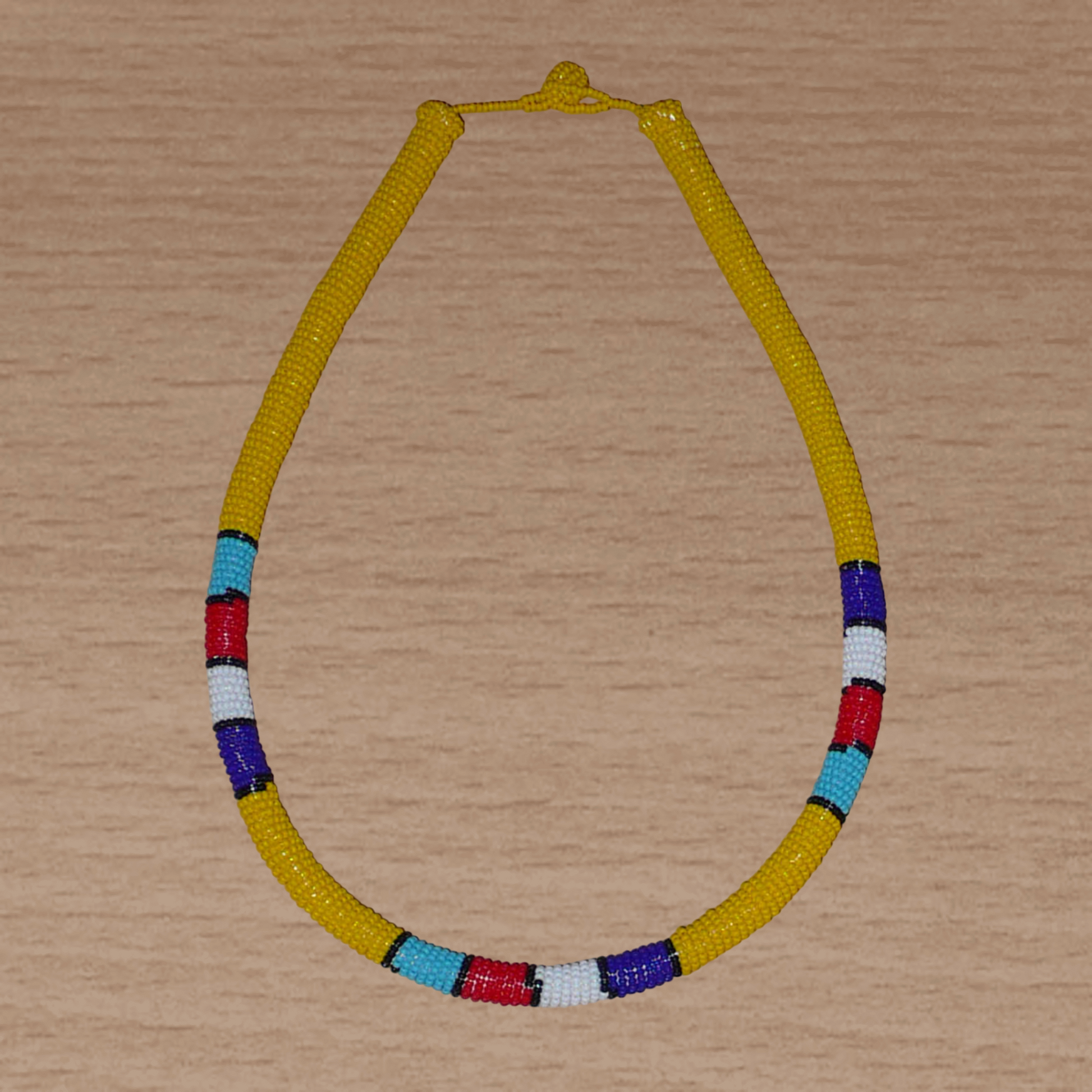 Collier africain tubulaire jaune à motifs ethniques traditionnels zoulous composé de perles de rocaille enroulées autour d'un tube en plastique.