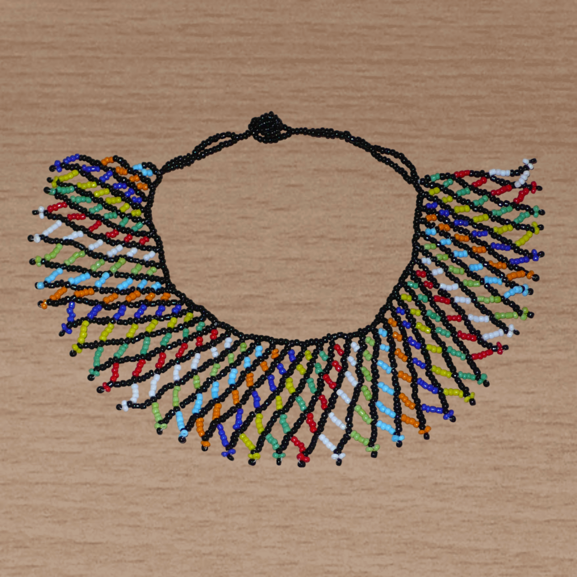 Collier sud-africain traditionnel zoulou composé d'une dentelle perlée faite de perles de rocaille noire et multicolores entrelacées.
