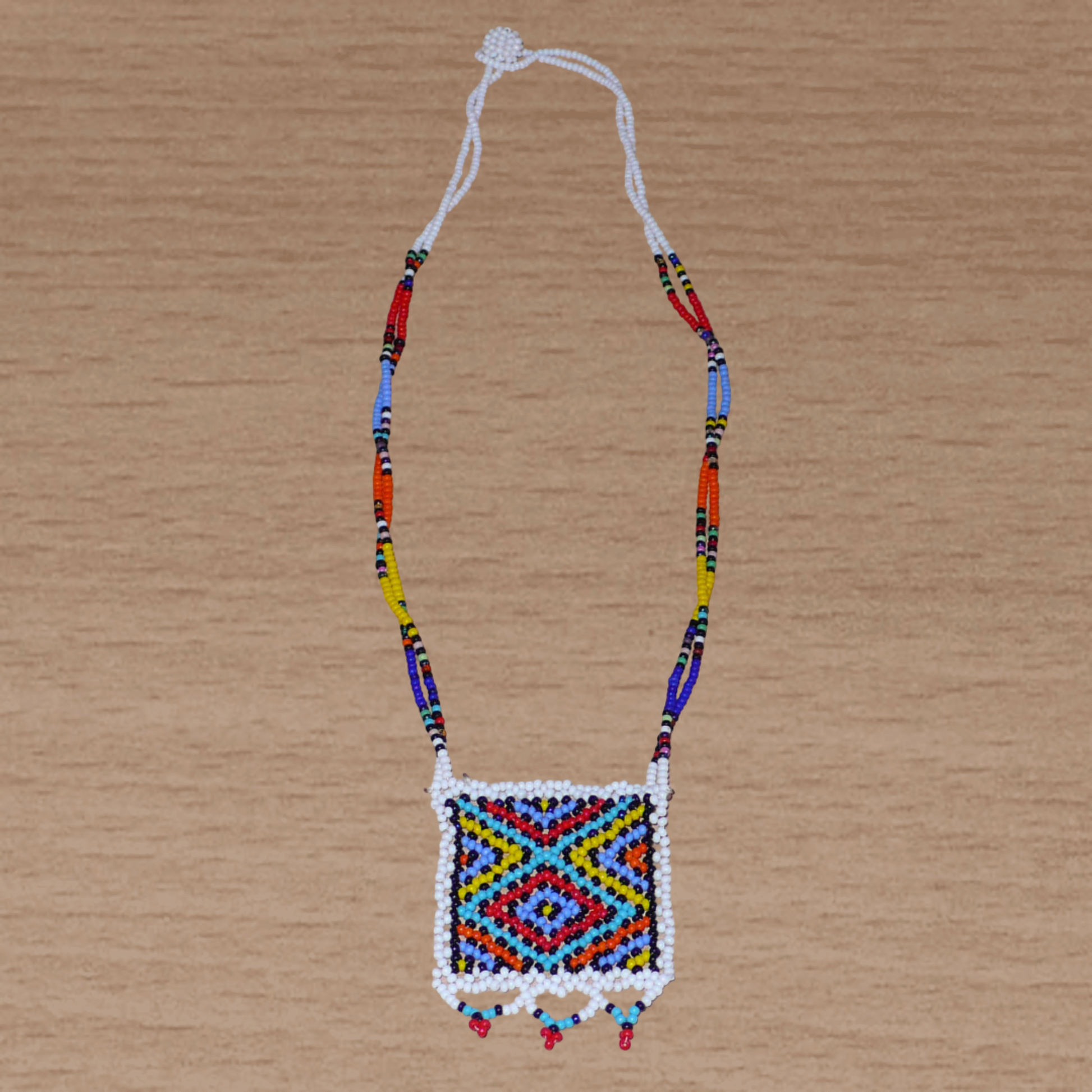 Collier africain zoulou en perles de rocaille blanches et multicolores agrémenté d'un pendentif carré à motifs ethniques traditionnels.