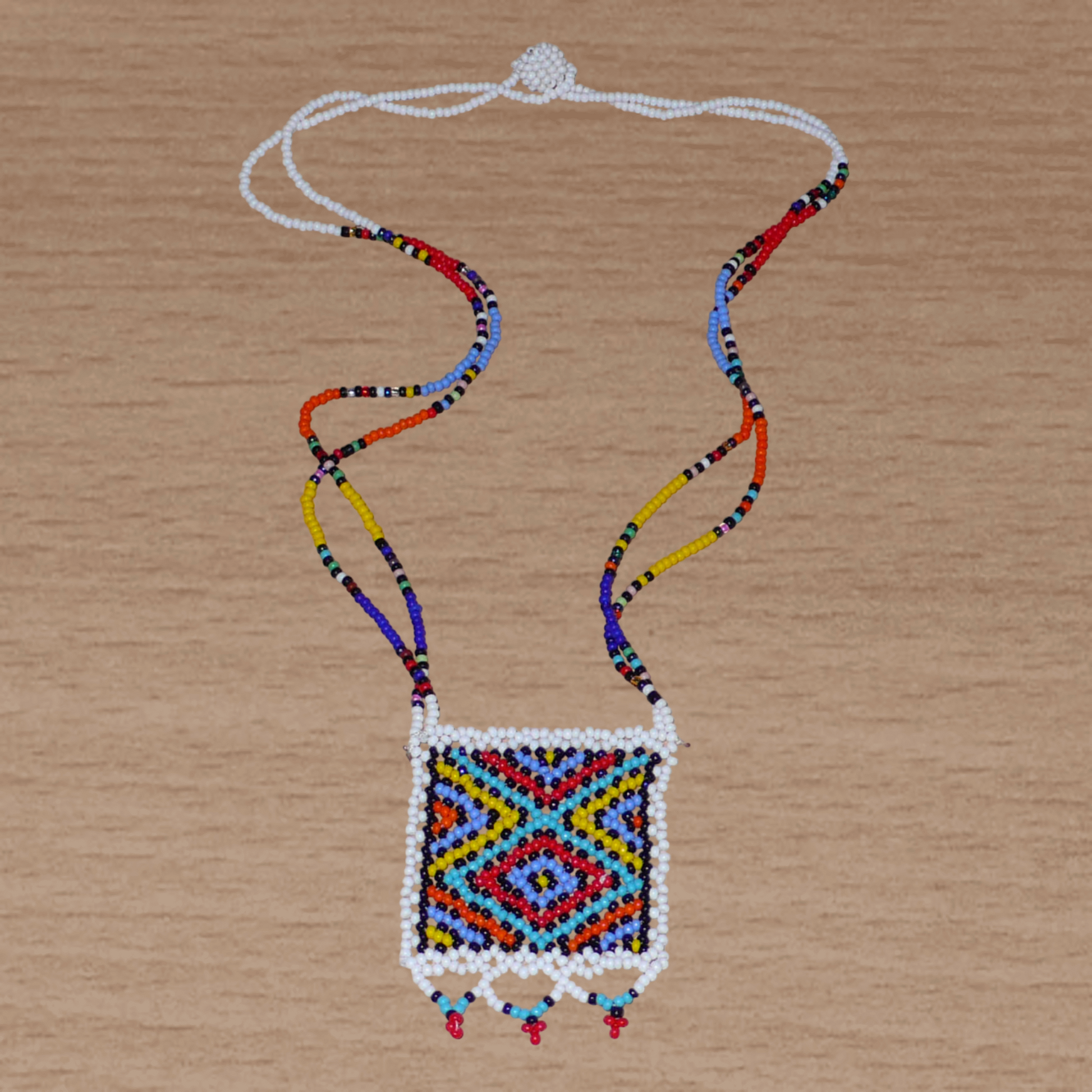 Collier africain zoulou en perles de rocaille blanches et multicolores agrémenté d'un pendentif carré à motifs ethniques traditionnels.