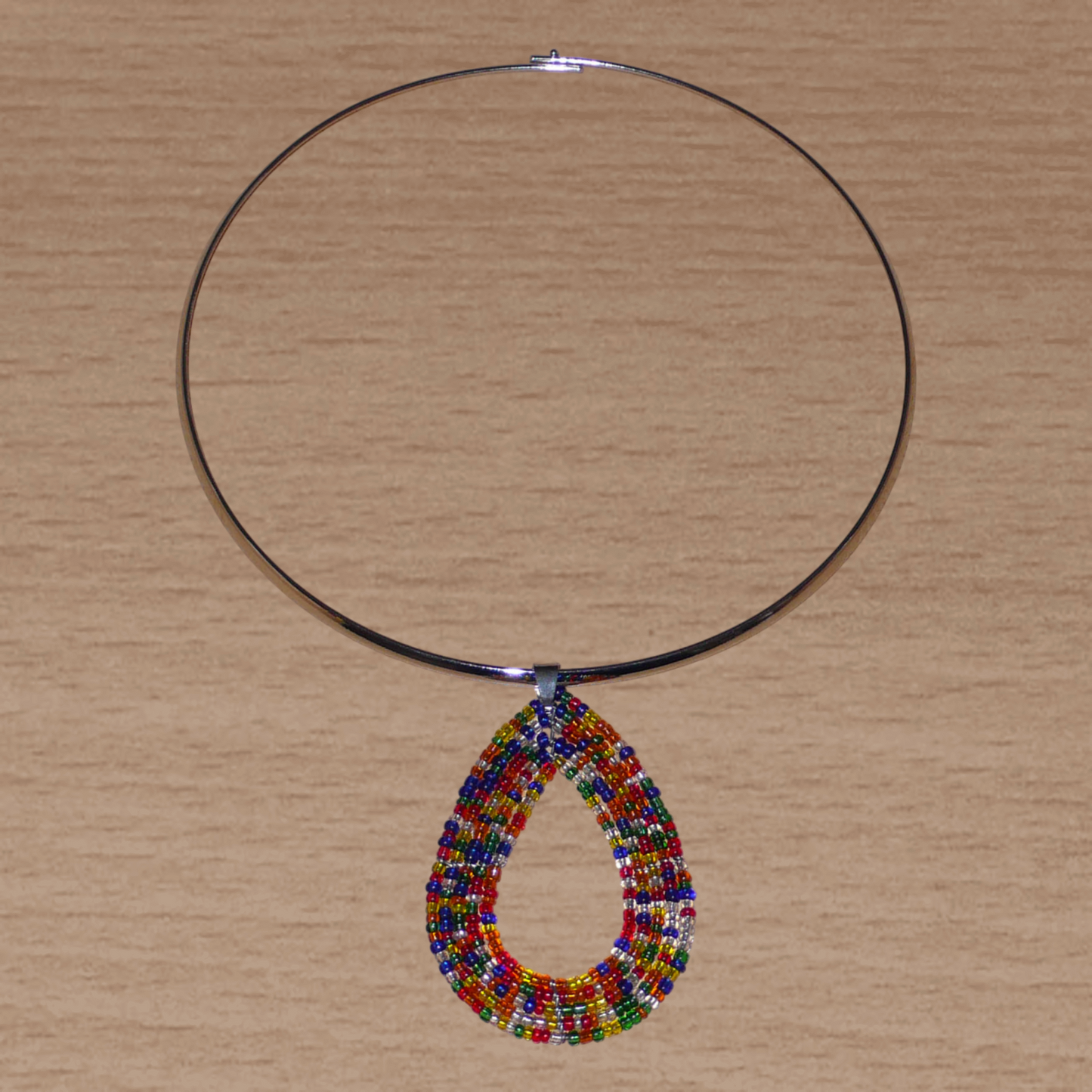 Collier ethnique contemporain composé d'un ras de cou en laiton orné d'un pendentif fait d'un mélange de perles de rocaille multicolores translucides montées en forme de goutte.