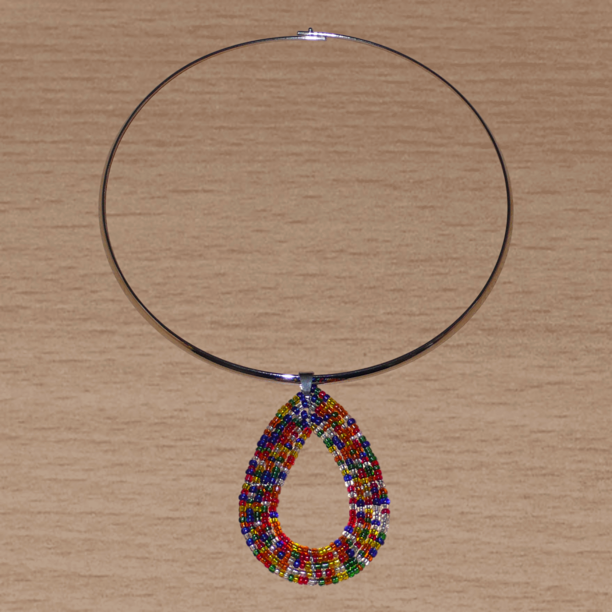 Collier ethnique contemporain composé d'un ras de cou en laiton orné d'un pendentif fait d'un mélange de perles de rocaille multicolores translucides montées en forme de goutte.