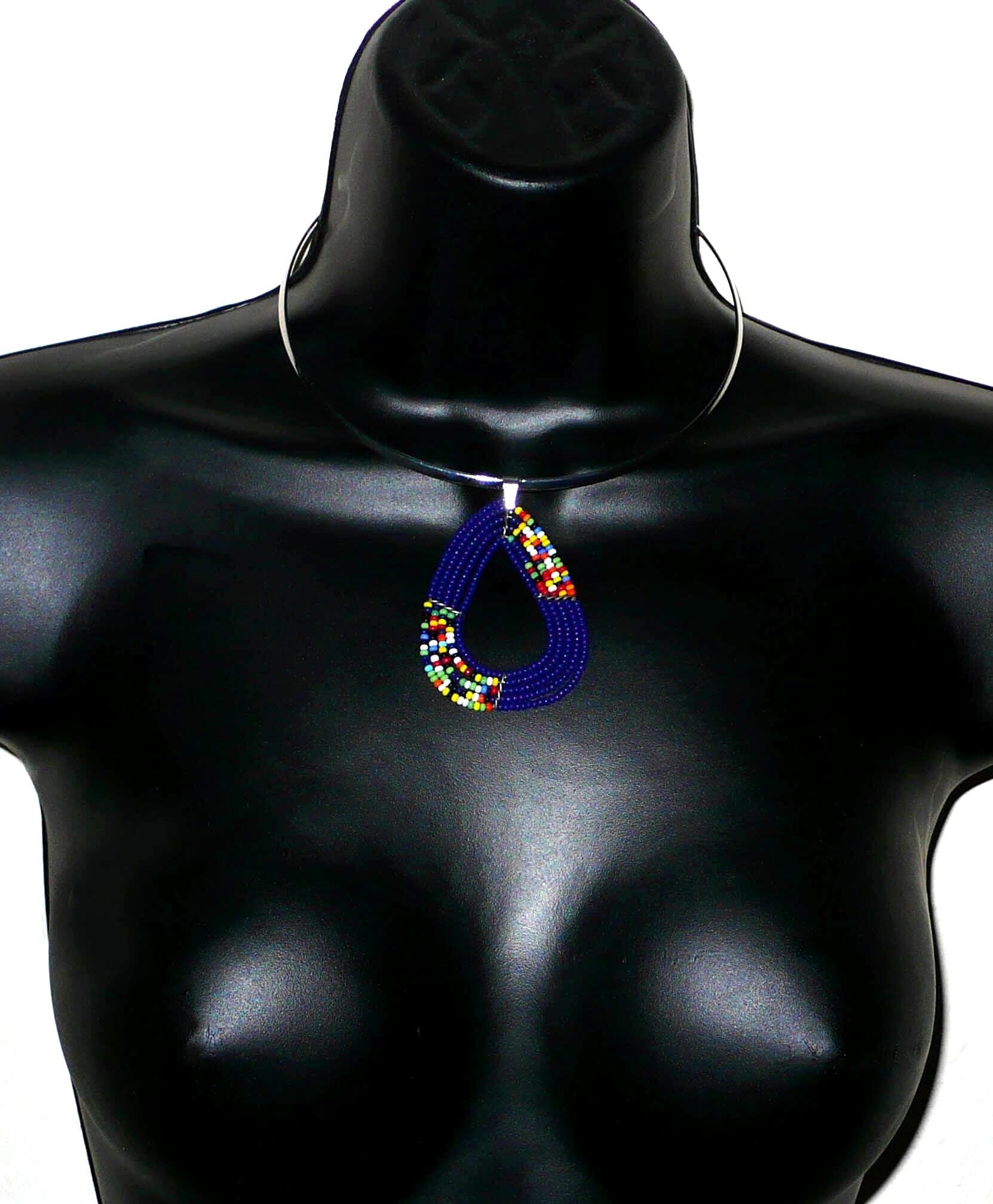 Collier ethnique composé d'un ras de cou en laiton agrémenté d'un pendentif de forme triangulaire aux angles arrondis fait de perles de rocaille bleu marine et multicolores.
