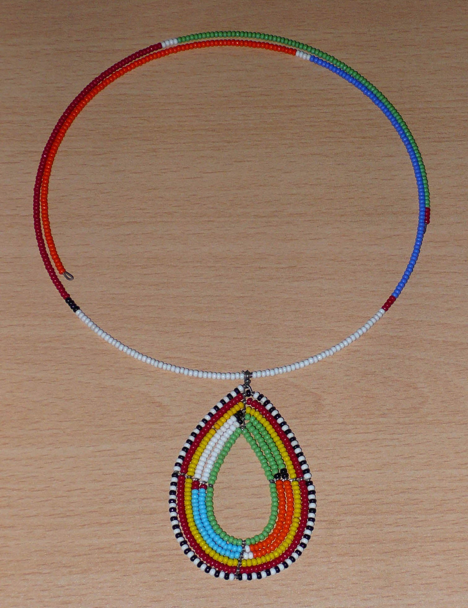 Collier ras de cou africain Massai orné d'un pendentif à motifs ethniques en forme de goutte fait de perles de rocaille colorées.