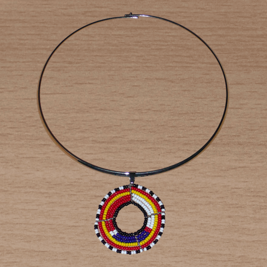 Collier ethnique contemporain se composant d'un ras de cou en laiton orné d'un pendentif rond à motifs Massai fait d'un tissage de perles de rocaille rouges, blanches, bleues, jaunes, noires et blanches.