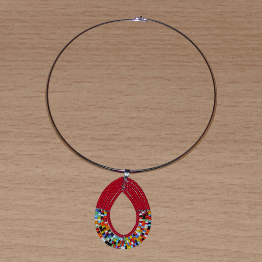 Collier ethnique rouge et multicolore composé d'un ras de cou en laiton orné d'un pendentif Massai en forme de goutte fait de perles de rocaille.