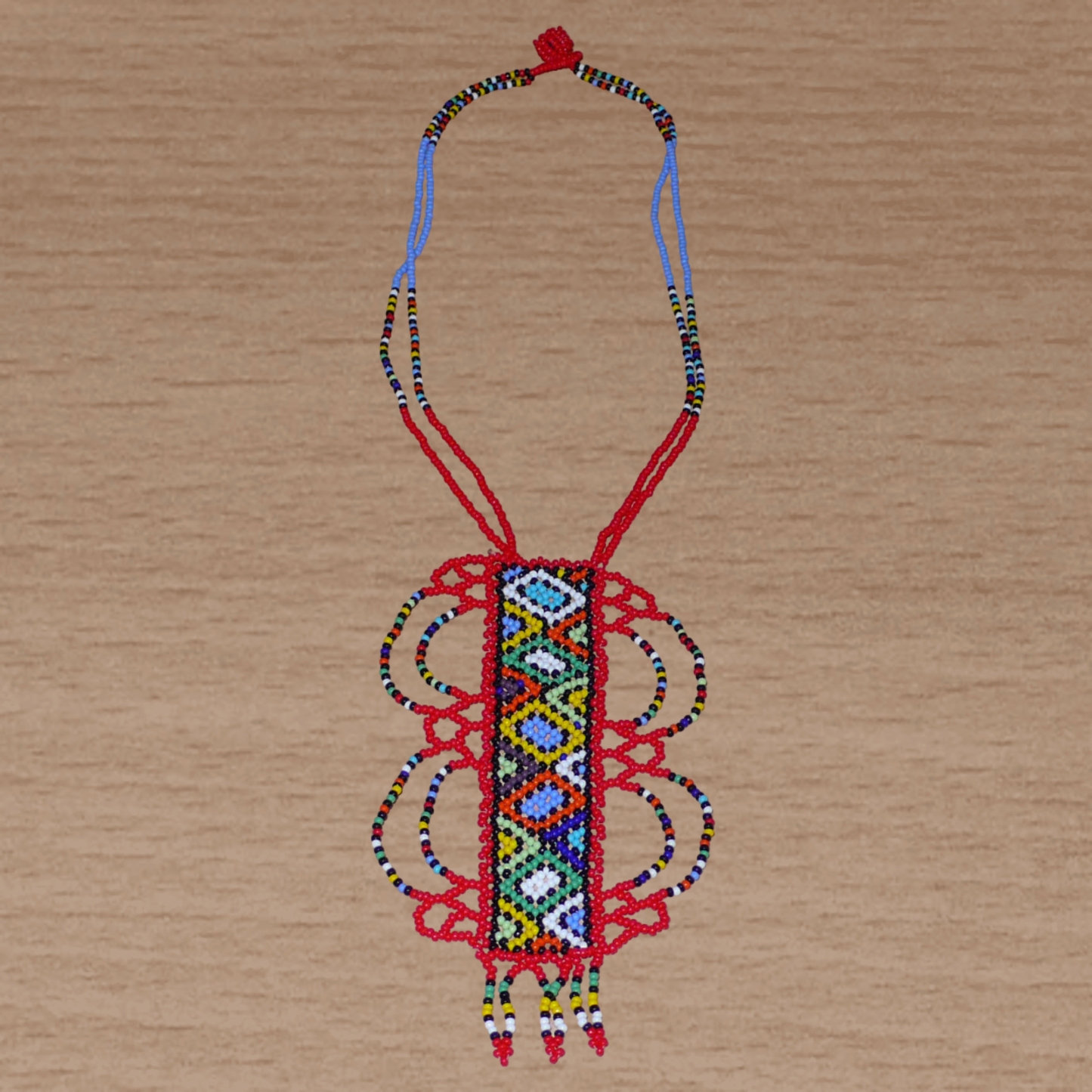 Collier sud-africain traditionnel rouge et multicolore agrémenté d'un long et large pendentif fantaisie en perles de rocaille.