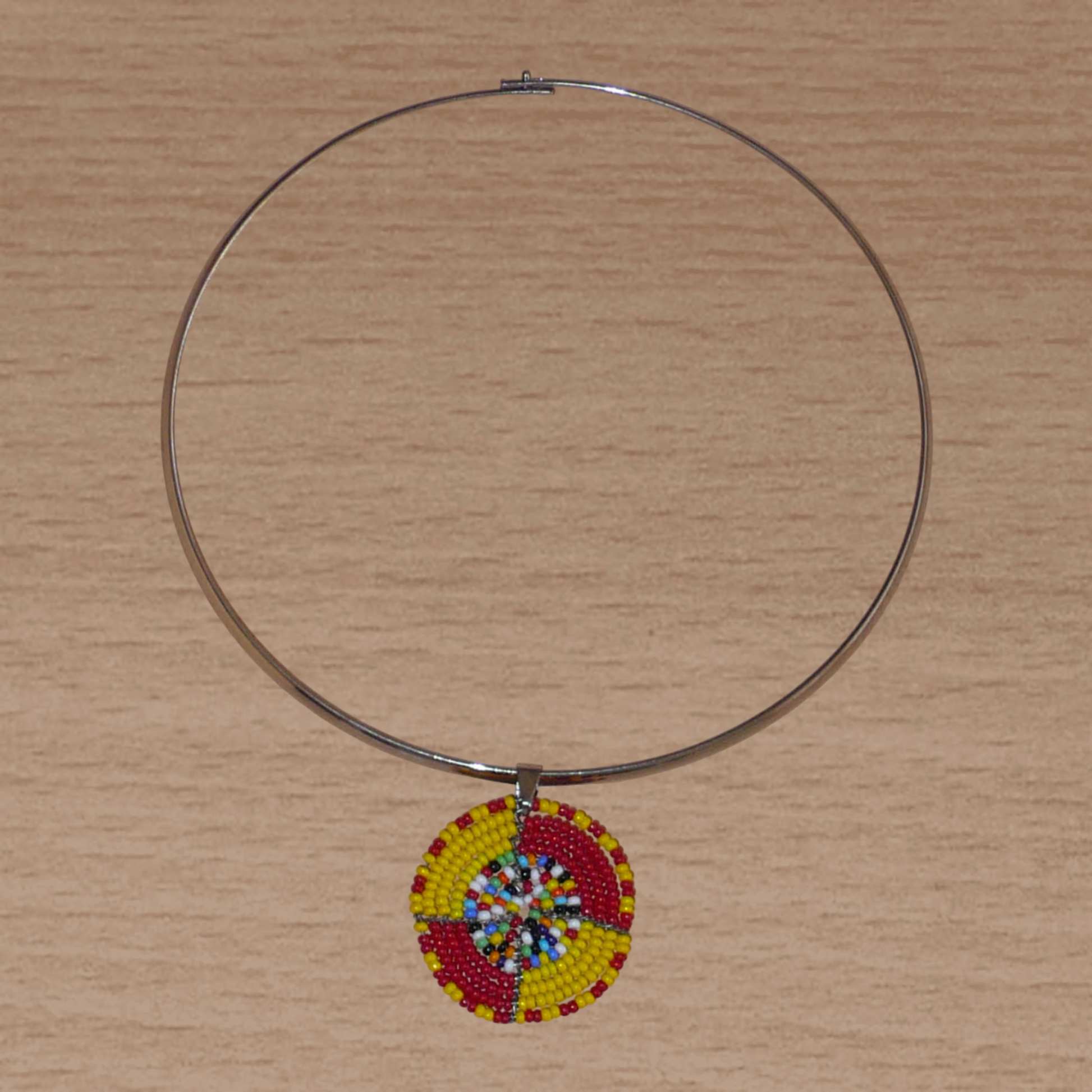 Collier ethnique composé d'un ras de cou en laiton rehaussé d'un petit médaillon Massai en perles de rocaille rouges, jaunes et multicolores.