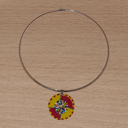 Collier ethnique composé d'un ras de cou en laiton rehaussé d'un petit médaillon Massai en perles de rocaille rouges, jaunes et multicolores.