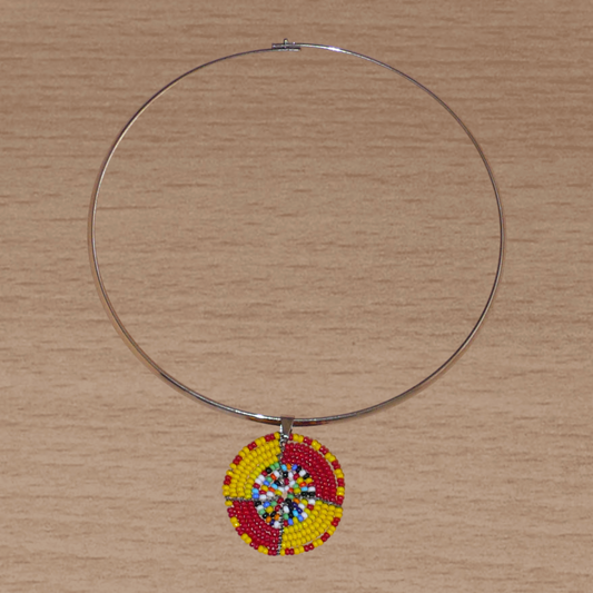 Collier ethnique composé d'un ras de cou en laiton rehaussé d'un petit médaillon Massai en perles de rocaille rouges, jaunes et multicolores.