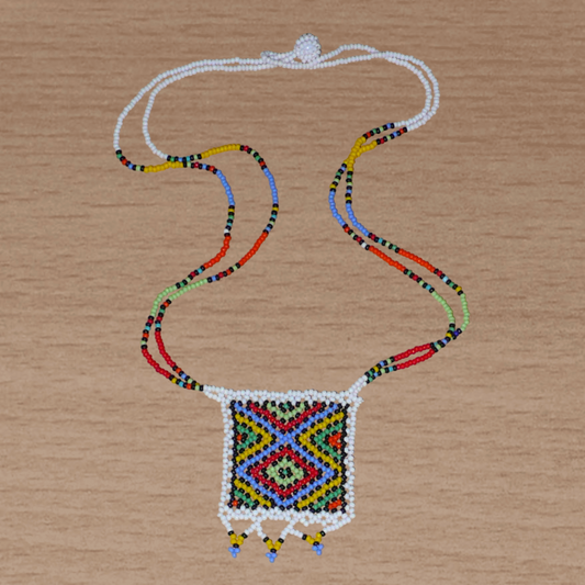 Collier sud-africain traditionnel orné d'un pendentif décoré de motifs ethniques zoulous ; il se compose d'un tissage de perles de rocaille blanches et multicolores et s'attache avec un fermoir à boule.