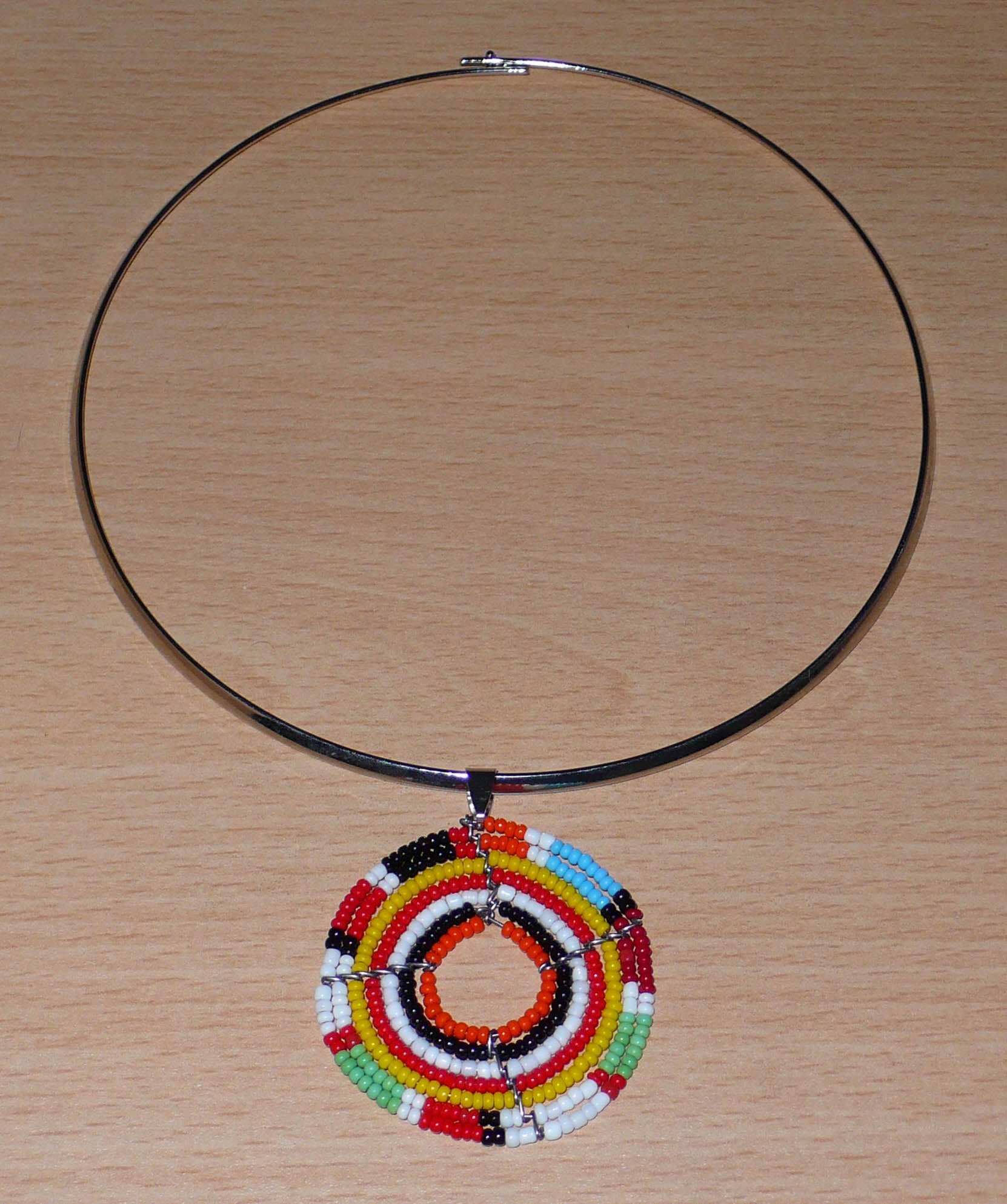 Bijou ethnique coloré composé d'un ras de cou en laiton rehaussé d'un médaillon Massai fait de perles de rocaille multicolores.