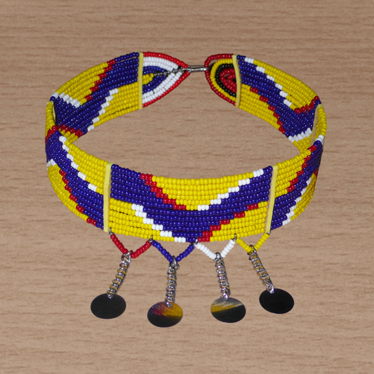 Collier multi-rangs africain Massai à motifs ethniques composé de douze rangées de perles de rocaille jaunes, bleu foncé, rouges et blanches et prolongé de chaînettes décorées de pastilles métalliques ; il se ferme avec un crochet.