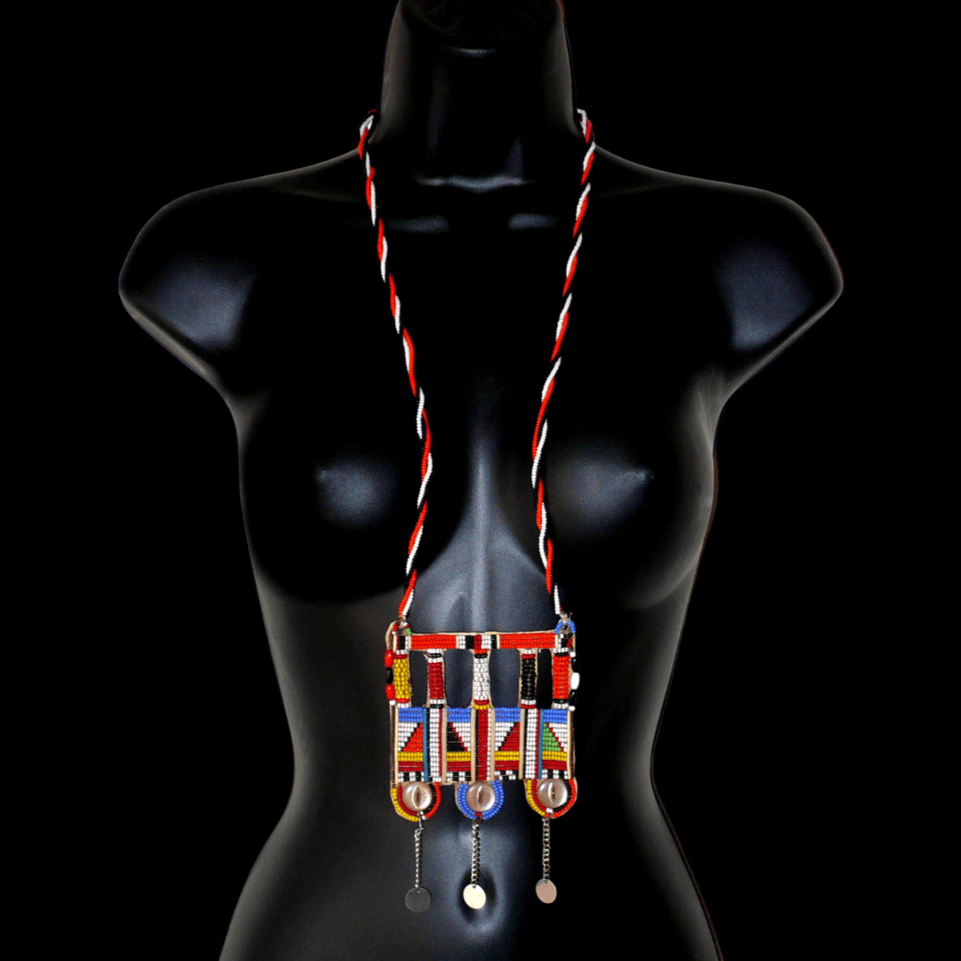 Authentique bijou africain Massai, ce long collier de style sautoir est orné d'un large pendentif à motifs ethniques fait de perles de rocaille multicolores et de boutons nacrés brodés sur un morceau de plastique recyclé ; ils se prolonge de chaînettes décorées de pastilles métalliques.