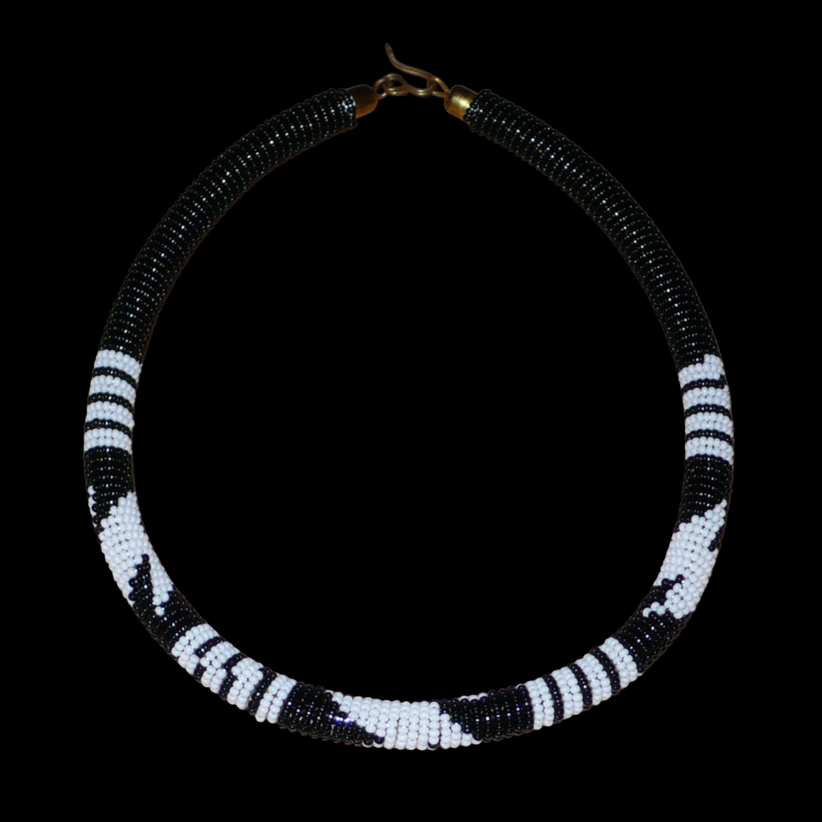 Collier africain tubulaire noir à motifs tribaux zoulous blancs composé de perles de rocaille tissées et enroulées autour d'un tube. Il s'attache avec un crochet.