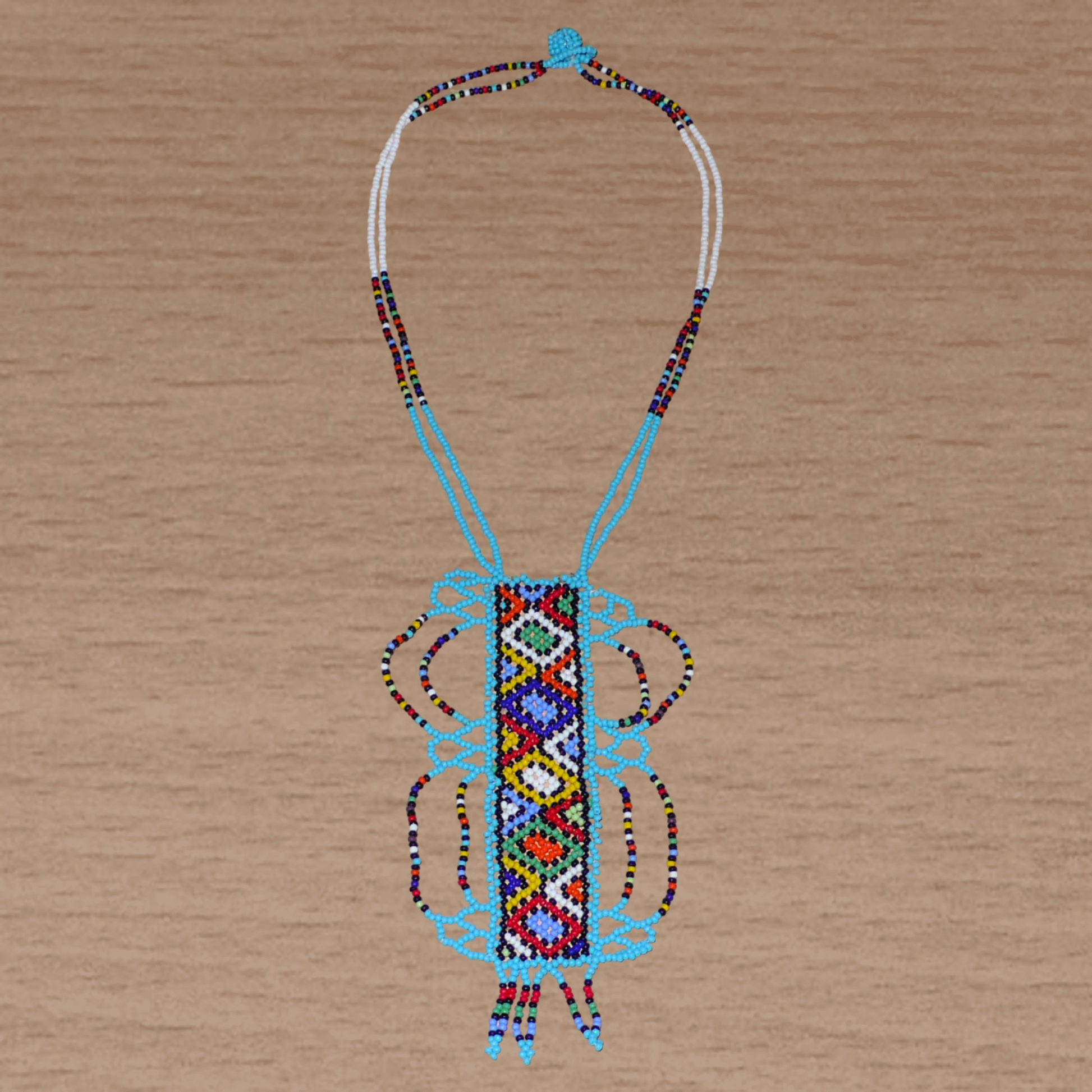 Collier sud-africain traditionnel bleu et multicolore agrémenté d'un long et large pendentif décoré de motifs ethniques zoulous.