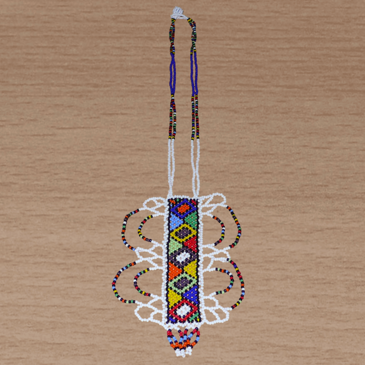 Collier sud-africain blanc et multicolore agrémenté d'un long et large pendentif fantaisie fait de perles de rocaille.