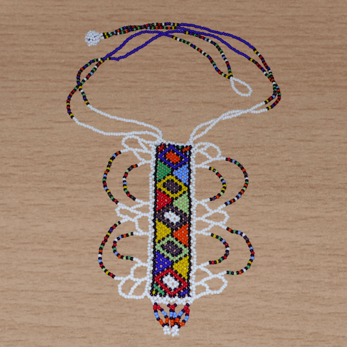 Collier sud-africain blanc et multicolore agrémenté d'un long et large pendentif fantaisie fait de perles de rocaille.