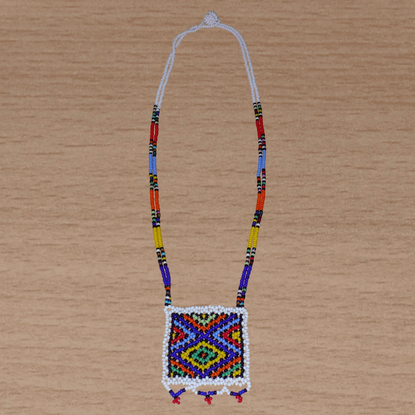 Collier sud-africain traditionnel "Zulu Love Letter" avec pendentif décoré de motifs ethniques zoulous composé d'un tissage de perles de rocaille blanches et multicolores.