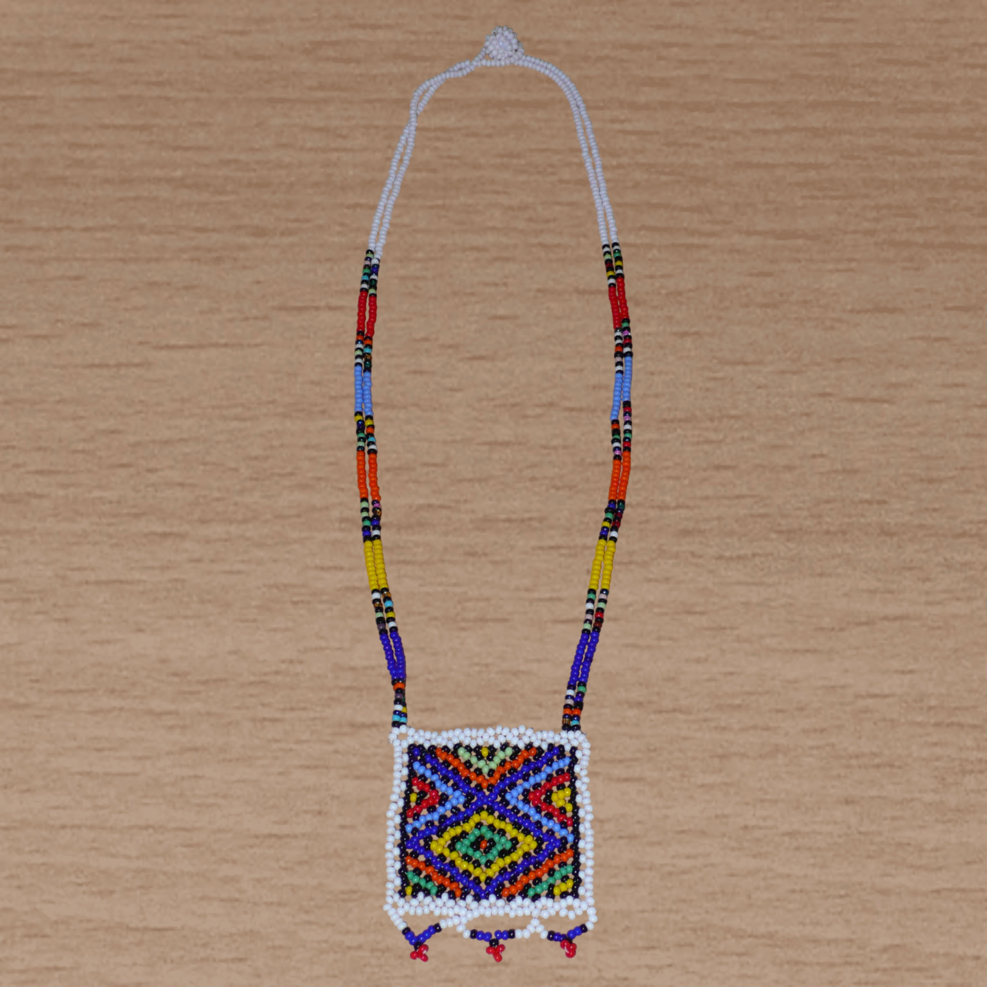 Collier sud-africain traditionnel "Zulu Love Letter" avec pendentif décoré de motifs ethniques zoulous composé d'un tissage de perles de rocaille blanches et multicolores.