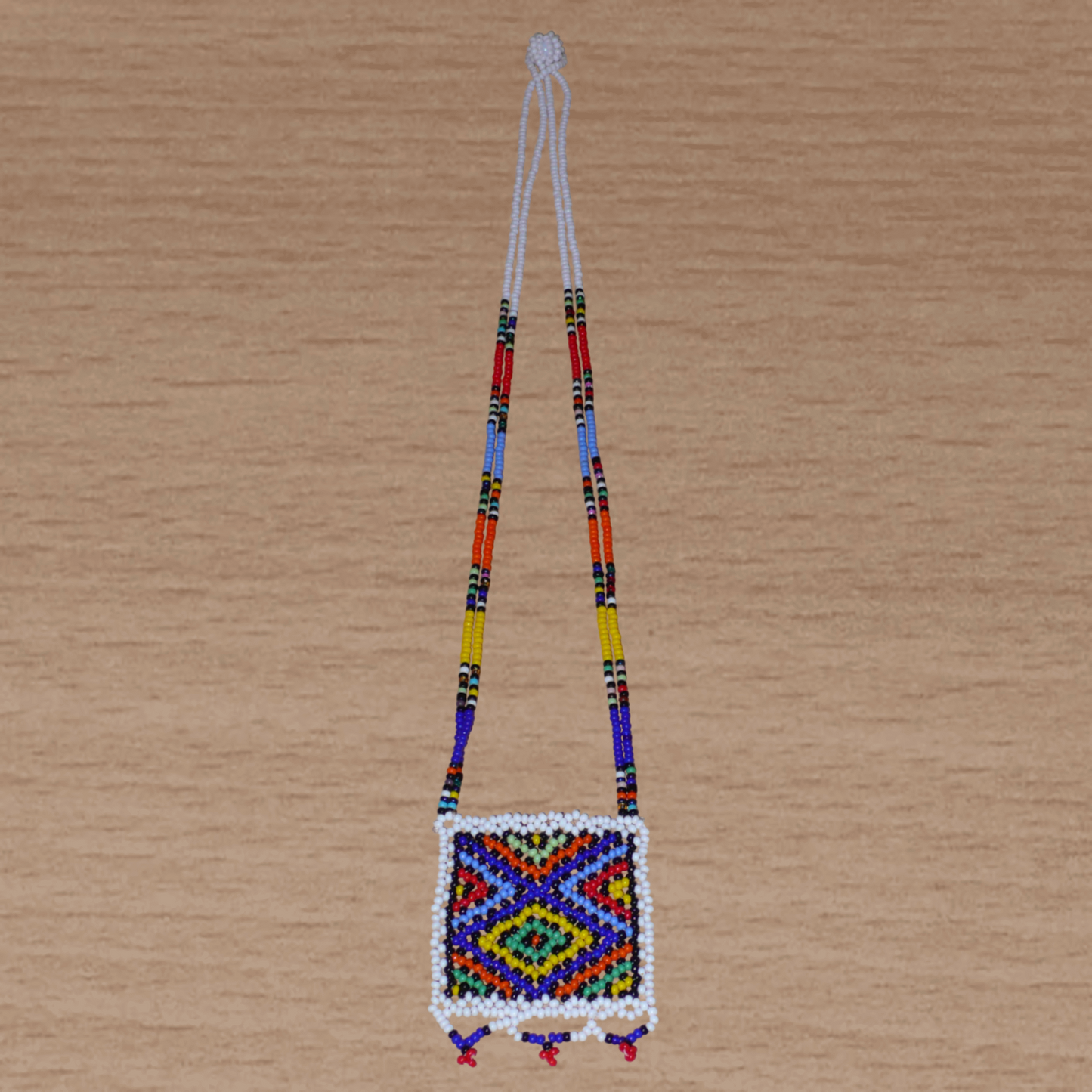 Collier sud-africain traditionnel "Zulu Love Letter" avec pendentif décoré de motifs ethniques zoulous composé d'un tissage de perles de rocaille blanches et multicolores.